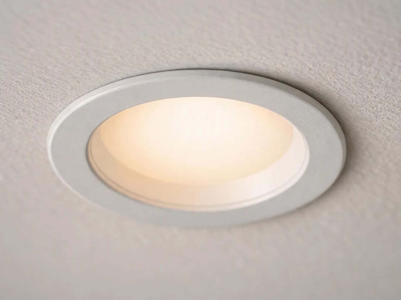 A recessed ceiling light glows softly in a textured white ceiling