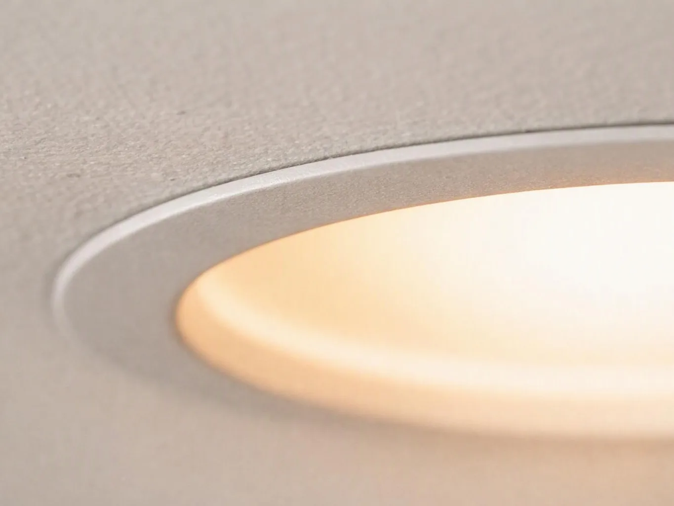 A recessed ceiling light glows warmly against a textured beige surface